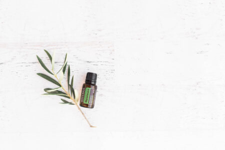 a small bottle of essential oil next to a branch